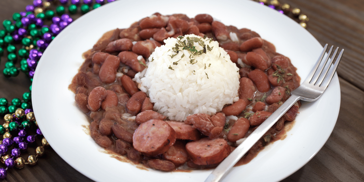 A bowl of New Orleans style red beans and rice surrounded by Mardi Gras beads